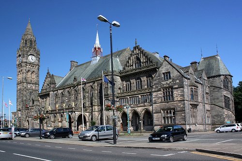 Rochdale Town Hall historic Gothic stone building with clock tower under blue sky. - Manchester Airport Taxi Transfer - Manchester Airport Taxi Transfer