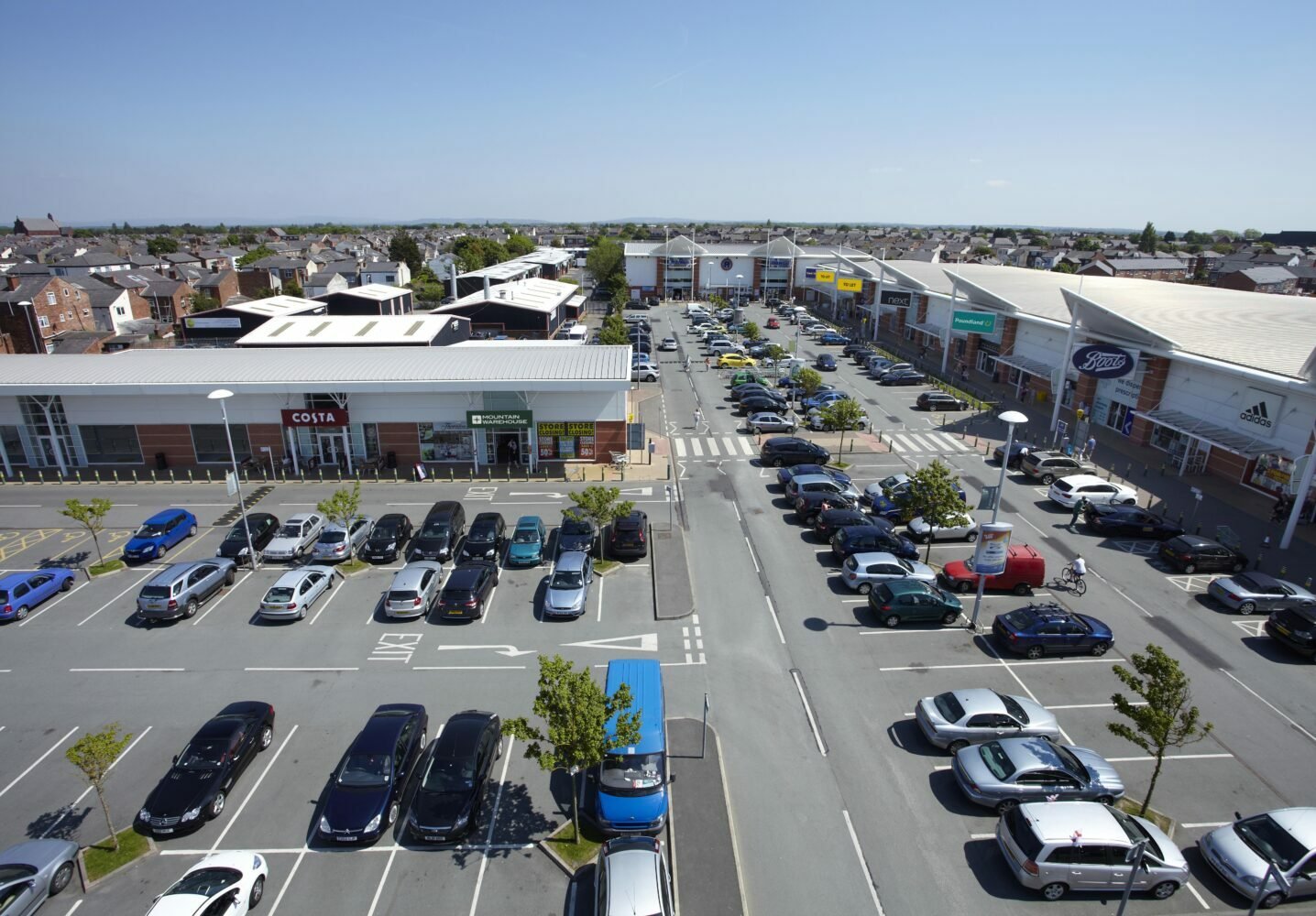 UK retail park aerial view with car park and high street stores. - Manchester Airport Taxi Transfer - Manchester Airport Taxi Transfer