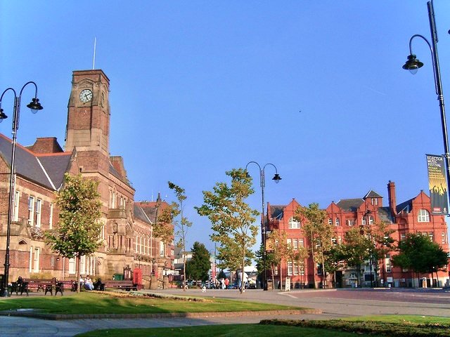 Historic town hall with clock tower and red brick buildings on sunny day - Manchester Airport Taxi Transfer - Manchester Airport Taxi Transfer