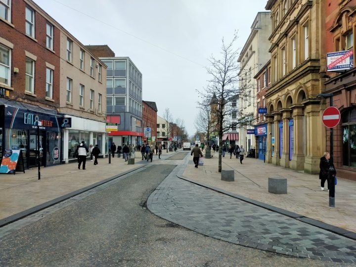 Busy UK town centre pedestrian high street on cloudy day - Manchester Airport Taxi Transfer - Manchester Airport Taxi Transfer