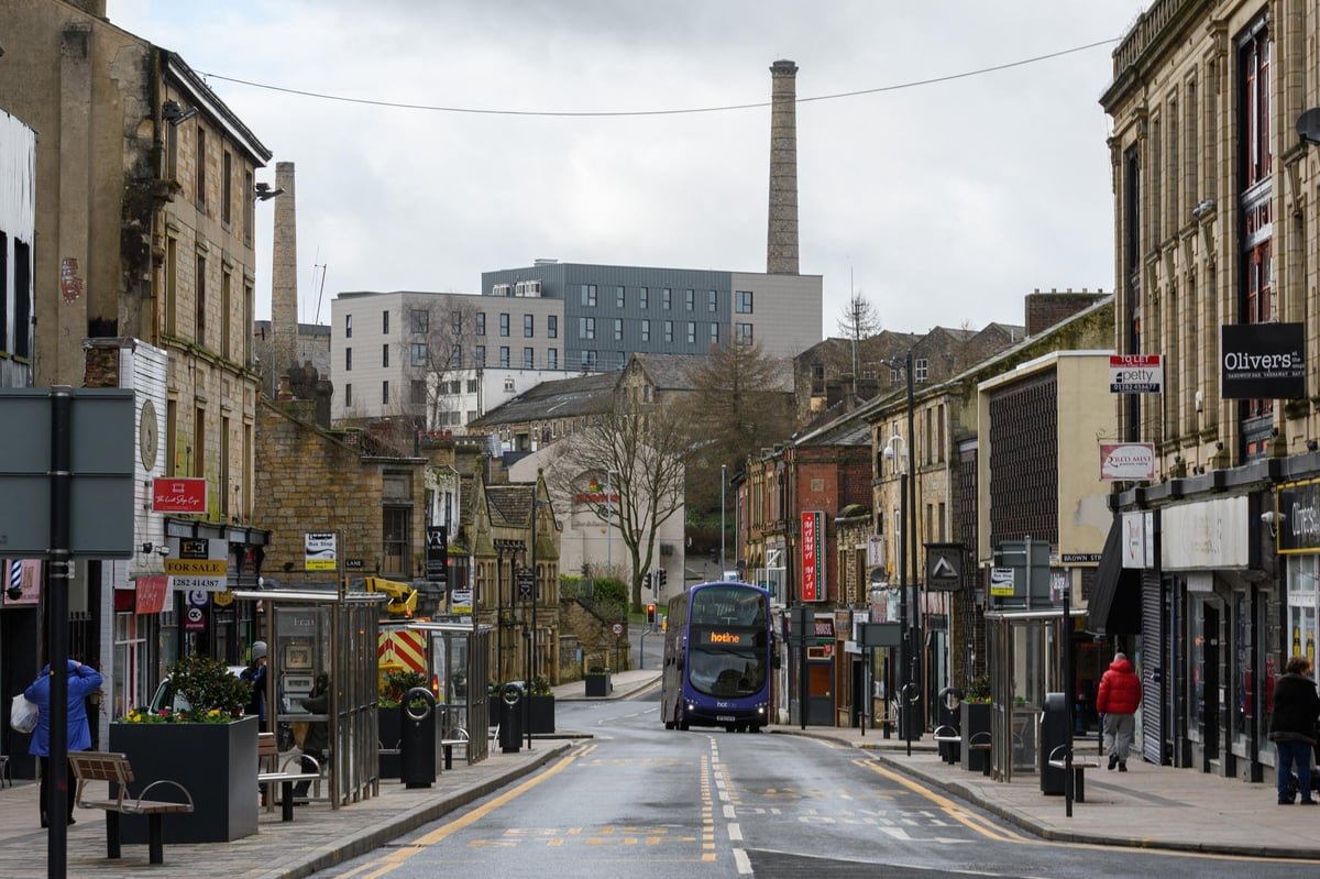 UK town high street with bus and industrial chimney skyline - Manchester Airport Taxi Transfer - Manchester Airport Taxi Transfer