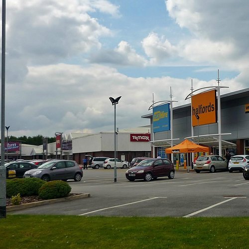 Halfords and TK Maxx retail park with busy car park - Manchester Airport Taxi Transfer - Manchester Airport Taxi Transfer