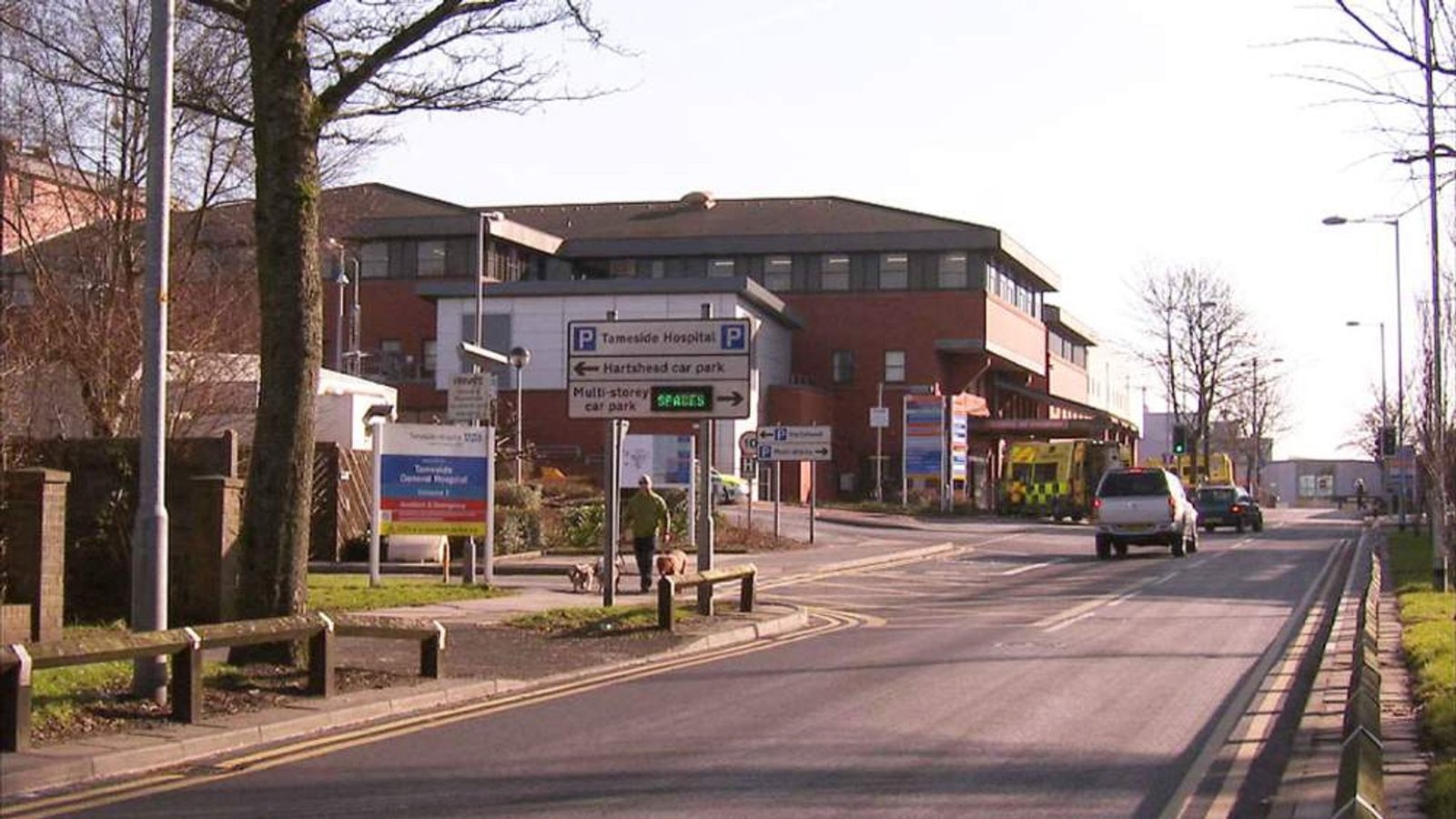 Tameside General Hospital entrance with road signs and ambulance. - Manchester Airport Taxi Transfer - Manchester Airport Taxi Transfer