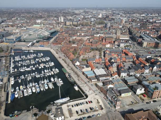 Aerial view of a harbor marina with many moored boats beside a dense town of red-brick buildings on the waterfront. - Manchester Airport Taxi Transfer - Manchester Airport Taxi Transfer
