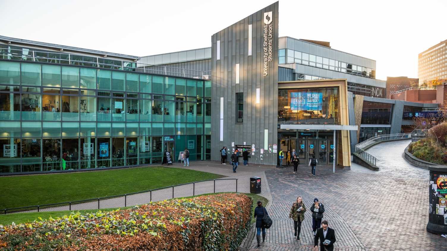 University of Sheffield Students' Union building with a glass-fronted campus facade and people walking outside on a cobblestone plaza. - Manchester Airport Taxi Transfer - Manchester Airport Taxi Transfer